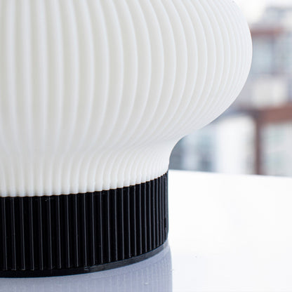 Gros plan sur le diffuseur nervuré et la base noire de la lampe Lumya