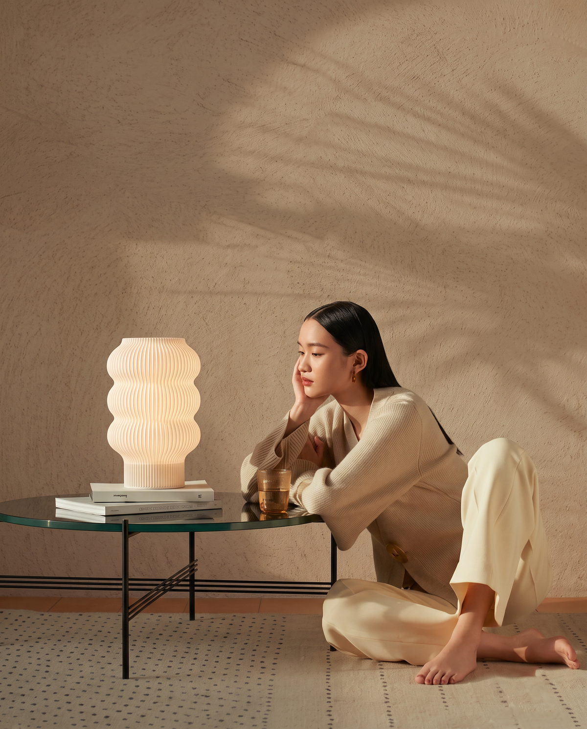Lampe Lumya à base rose posée sur des livres, éclairage doux dans le salon